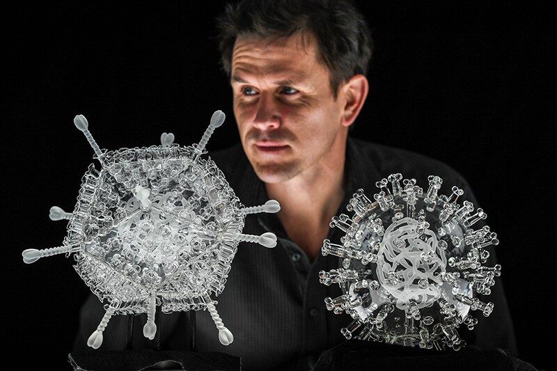 Artist Luke Jerram with his glass sculpture of the Oxford-AstraZeneca coronavirus vaccine (left) alongside his earlier work of the virus itself, in glass at the Paintworks on February 05, 2021 in Bristol, England. The sculpture, which is one million times larger than the actual vaccine nanoparticle, marks the ten millionth vaccination to be administered in the UK. Five limited editions of the artwork will be sold with all profits going to the global charity Médecins Sans Frontières to help communities heavily impacted by the pandemic. Testing positive for Covid-19 himself in November, Jerram says he is still feeling the effects of the virus. "When I created a sculpture of Covid-19 back in March, little did I know I would later be among those to contract the virus."