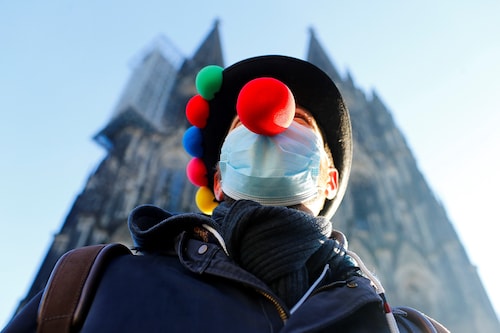 A lonesome reveller poses in front of Cologne Cathedral after carnival festivities were cancelled due to the coronavirus disease (COVID-19) pandemic in Cologne, Germany, February 11, 2021.