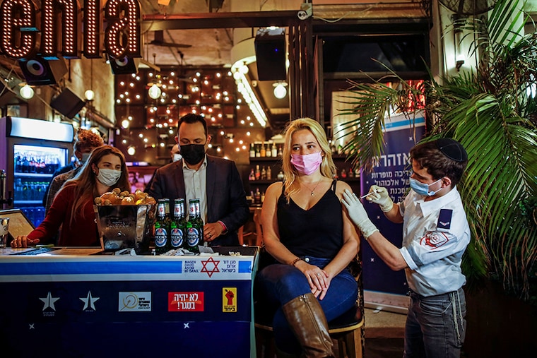 A woman receives a vaccination against the coronavirus disease (COVID-19) as part of a Tel Aviv municipality initiative offering a free drink at a bar to residents getting the shot, in Tel Aviv, Israel February 18, 2021.
