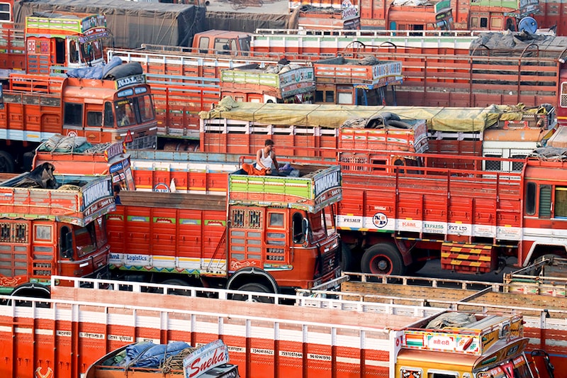 A man sits in the toolbox of his parked truck at a terminal during a nationwide strike to protest against rising fuel prices and the Goods and Services Tax (GST) rules, in Mumbai, India, February 26, 2021.