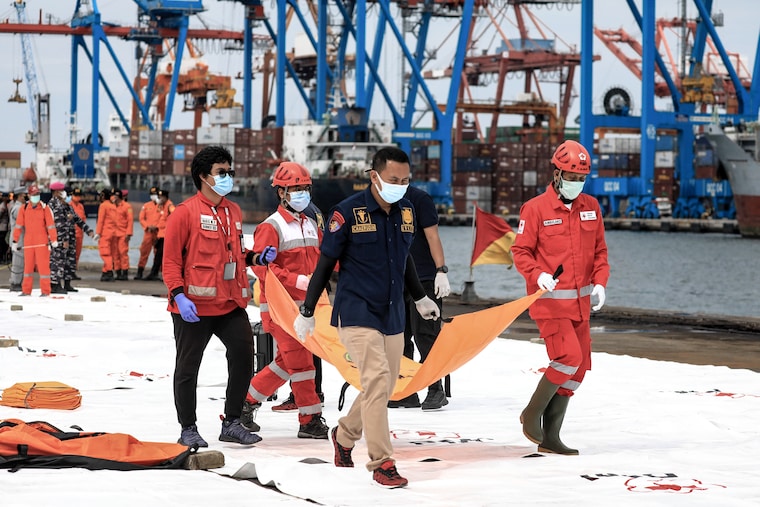 Indonesian Search and Rescue (SAR) team and military officers carrying a bag with suspected body parts of victims during the search at Tanjung Priok Port.Sriwijaya Air flight SJ182 with 62 people on board from Jakarta to Pontianak, Indonesia, lost contact with air controllers shortly after take-off and crashed into the waters off the coast of Jakarta. Indonesian authorities say they have found the location where they believe the plane crashed into the sea.