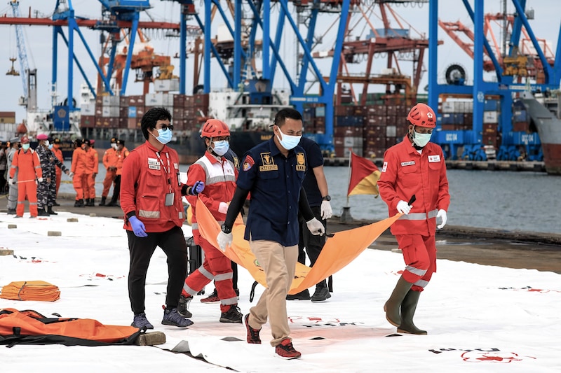 Indonesian Search and Rescue (SAR) team and military officers carrying a bag with suspected body parts of victims during the search at Tanjung Priok Port.Sriwijaya Air flight SJ182 with 62 people on board from Jakarta to Pontianak, Indonesia, lost contact with air controllers shortly after take-off and crashed into the waters off the coast of Jakarta. Indonesian authorities say they have found the location where they believe the plane crashed into the sea.