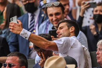 Novak Djokovic of Serbia takes a selfie with a member of the crowd after beating Mateo Berrettini of Italy in the final of the gentlemen"s singles during Day Thirteen of The Championships - Wimbledon 2021 at All England Lawn Tennis and Croquet Club on July 11, 2021 in London, England.