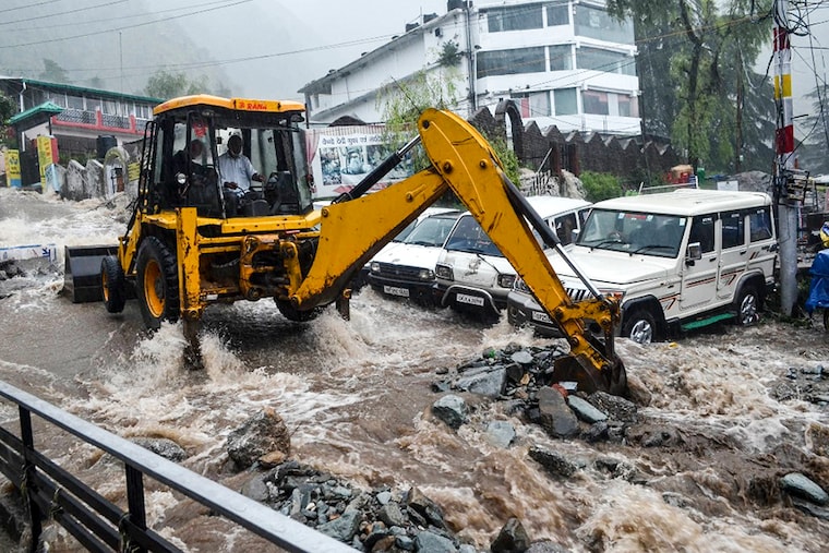 A worker uses an excavator to clear a road damaged by flash floods following heavy rains in Bhagsunag, about 10 km from Dharamshala on July 12, 2021.