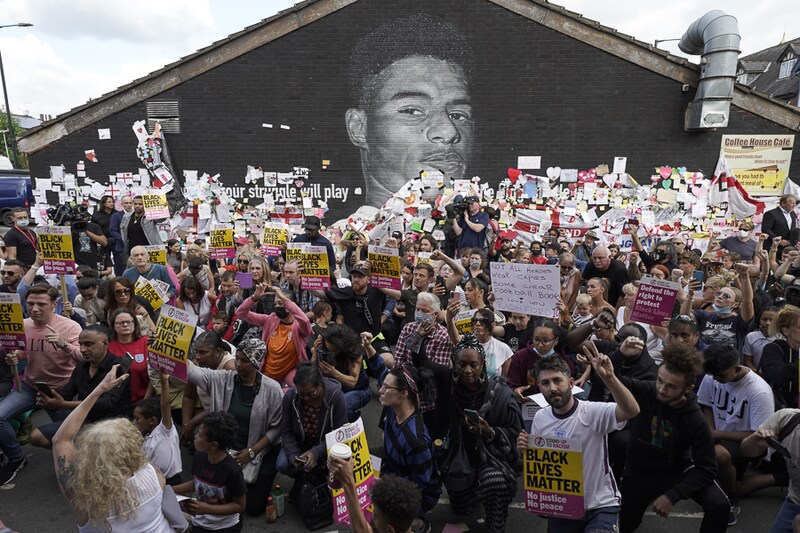 Anti-racism protestors take the knee during a demonstration in support of England player Marcus Rashford in front of his vandalised mural on the wall of the Coffee House Cafe in Withington, July 13, 2021. The mural appeared vandalised after substitute Marcus Rashford"s shot missed the goalpost during penalties and the England football team lost the UEFA Euro 2021 final.
