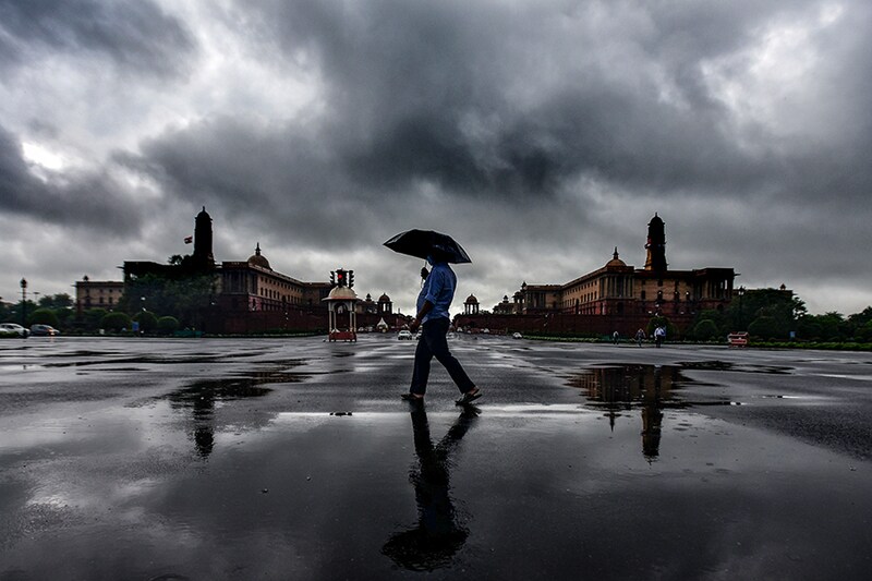 People enjoying rain shower at Vijay Chowk near North Block and South Block on July 14, 2021 in New Delhi, India. Rains lashed Delhi NCR for the second consecutive day on Wednesday, leading to heavy waterlogging on major roads and low-lying residential areas, and disrupting traffic for long hours. The maximum temperature settled at 35 degrees Celsius, normal for this time of the year.