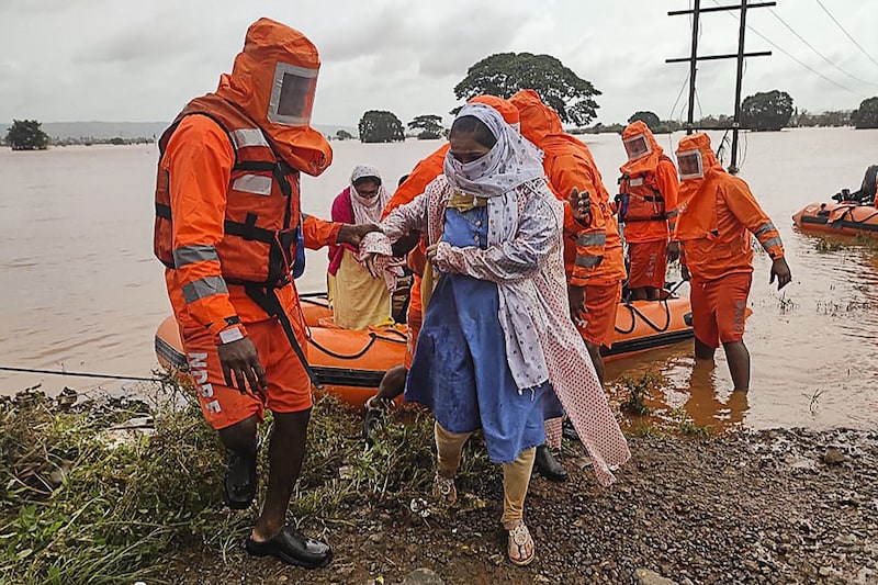 India"s National Disaster Response Force (NDRF) personnel rescue stranded villagers from flooded areas following heavy monsoon rains in Balinge village, Kolhapur district, Maharashtra, July 25, 2021. Over 1.4 lakh people have been evacuated and over 1.5 lakh hectares of farm land and crops are reportedly damaged across the state.