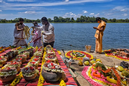 People decorate over 560 unclaimed clay urns with flowers on the banks of the Cauvery River before a mass immersion ritual organised by the government of Karnataka in Belakavadi Village in Mandya District, situated about 125 km from Bengaluru on June 2, 2021. The urns contain the ashes of people who died due to Covid-19.