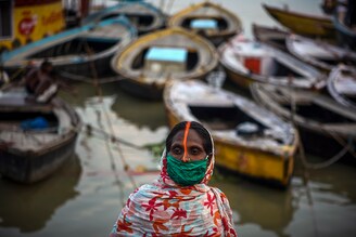 A woman attends evening prayers at the Dashashwmedh Ghat along the banks of the Ganges river in Varanasi, as Uttar Pradesh, India"s most populous state, reopens on June 21, 2021. India has seen a steady fall in its Covid-19 infection numbers over the last three weeks after a devastating May. Many states and cities have made tentative steps towards reopening fully, though the number of people vaccinated as a share of the overall population remains in the single digits and experts raise concerns that reopening too quickly could once again risk recent gains made in fighting the coronavirus.