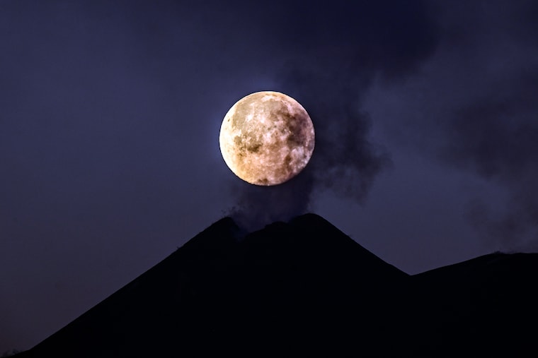 The full moon sets behind the southeast crater of Mount Etna, steaming in apparent stillness on February 28, 2021 in Catania, Italy. The shots were taken thanks to coordinates provided by astrophysicist Massimo Cecconi of the Galileo National Telescope in La Palma, Canary Islands, Spain. Mount Etna, Europe"s highest active volcano and one of the world"s most active volcanoes, has in recent weeks experienced numerous paroxysms with ash emissions from its south-east crater.