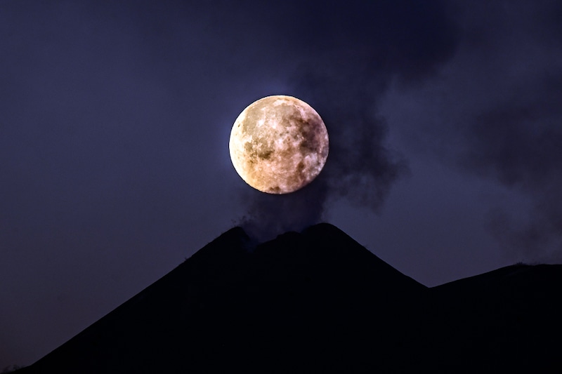 The full moon sets behind the southeast crater of Mount Etna, steaming in apparent stillness on February 28, 2021 in Catania, Italy. The shots were taken thanks to coordinates provided by astrophysicist Massimo Cecconi of the Galileo National Telescope in La Palma, Canary Islands, Spain. Mount Etna, Europe"s highest active volcano and one of the world"s most active volcanoes, has in recent weeks experienced numerous paroxysms with ash emissions from its south-east crater.