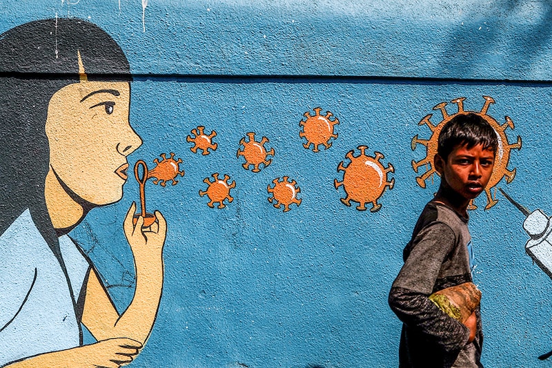 A boy walks past a graffiti amidst the spread of the coronavirus disease (COVID-19) on a street in Navi Mumbai. Corona virus cases have been rising in Maharashtra. India, March 5, 2021.