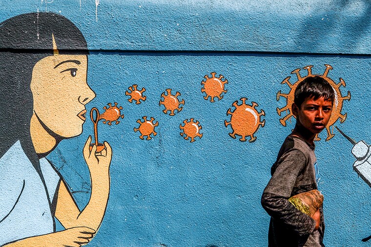A boy walks past a graffiti amidst the spread of the coronavirus disease (COVID-19) on a street in Navi Mumbai. Corona virus cases have been rising in Maharashtra. India, March 5, 2021.