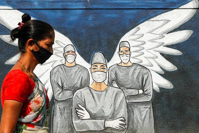 A woman wearing a protective mask walks past a graffiti amidst the spread of the coronavirus disease (COVID-19), on a street in Navi Mumbai, India, March 8, 2021.