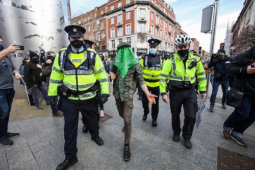 Irish Garda Police officers escort away an anti-lockdown protestor on St Patrick"s Day in Dublin on March 17, 2021, as official St Patrick"s day celebrations have been cancelled for the second year in a row due to the coronavirus pandemic. St Patrick"s Day is traditionally a bonanza trading day for publicans across the Republic of Ireland. Huge crowds heave into city centres on the national holiday, jamming pubs cheek by jowl and spilling out into the streets in an alcohol-fuelled, shamrock-themed celebration of the Emerald Isle.