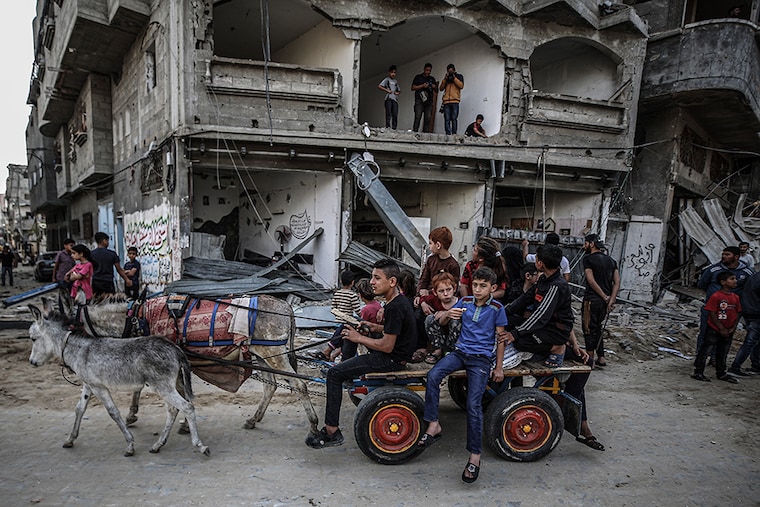 Palestinian kids are seen on a cart after Israel"s attack damaged streets in Gaza City, Gaza on May 20, 2021.