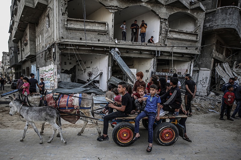 Palestinian kids are seen on a cart after Israel"s attack damaged streets in Gaza City, Gaza on May 20, 2021.