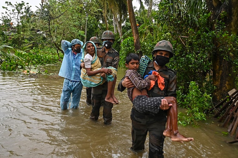 Indian army personnel wade through the flooded village roads carrying people to safety as Cyclone Yaas barrels towards India"s eastern coast in the Bay of Bengal, in Ramnagar some 180 kms from Kolkata on May 26, 2021.