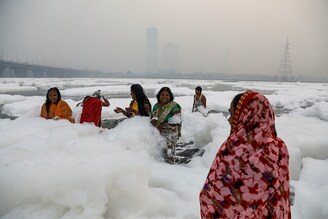 Women bathe in the polluted waters of the river Yamuna on a smoggy morning as Chhath Puja begins in New Delhi, November 8, 2021. Pollution in Yamuna is rising since a few days because of high levels of ammonia in it.