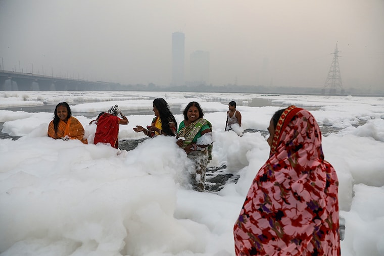 Women bathe in the polluted waters of the river Yamuna on a smoggy morning as Chhath Puja begins in New Delhi, November 8, 2021. Pollution in Yamuna is rising since a few days because of high levels of ammonia in it.