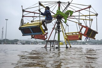 A boy clings to a merry-go-round ride in a flooded section of Marina beach following a heavy monsoon rainfall in Chennai on November 9, 2021. There seems to be no relief for Tamil Nadu as the Meteorological department has predicted extremely heavy rainfall across the state for the next couple of days.