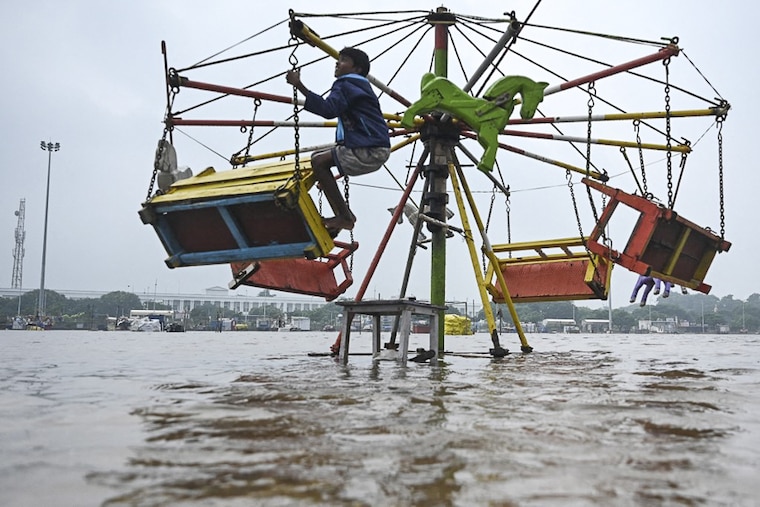 A boy clings to a merry-go-round ride in a flooded section of Marina beach following a heavy monsoon rainfall in Chennai on November 9, 2021. There seems to be no relief for Tamil Nadu as the Meteorological department has predicted extremely heavy rainfall across the state for the next couple of days.