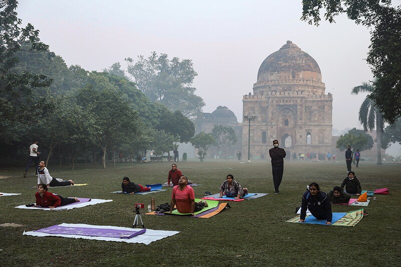 People doing yoga on a smoggy morning at Lodhi Garden in New Delhi, India, November 16, 2021.