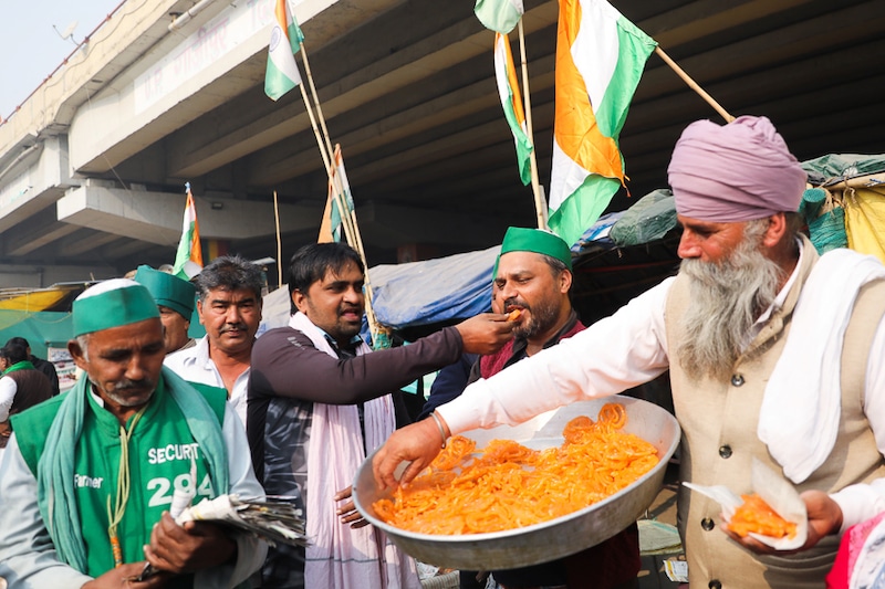Farmers feed each other sweets and celebrate as they pose for pictures after Indian Prime Minister Narendra Modi announced that he will repeal the controversial farm laws, at the Ghazipur farmers protest site near Delhi-UP border, India, November 19, 2021.