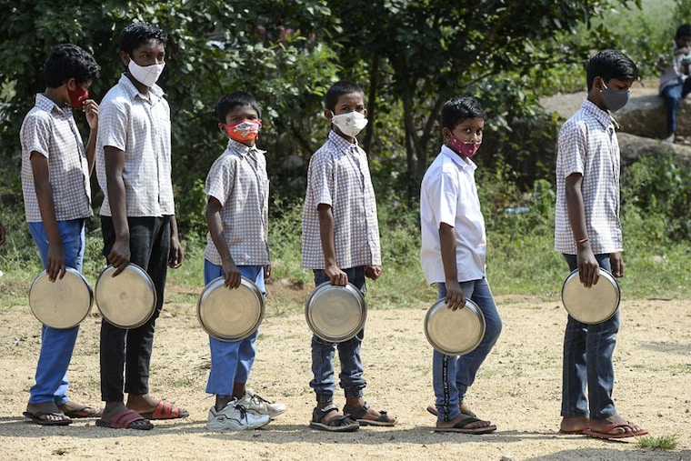Students stand in a queue to collect their mid-day meal during lunch break at a government high school on the outskirts of Hyderabad on November 23, 2021, as schools reopen after months due to the Covid-19 pandemic.