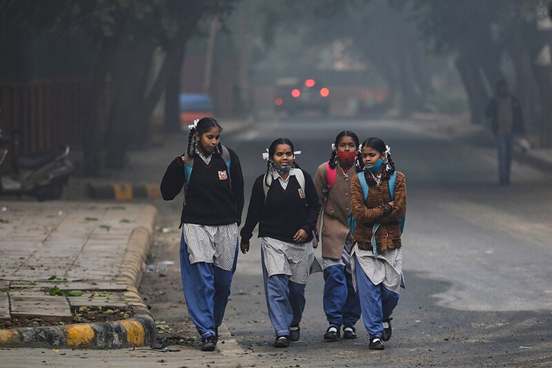 School girls walk towards a school as they reopened after remaining closed for nearly 15 days due to a spike in air pollution, on a smoggy morning in New Delhi, India, November 29, 2021.