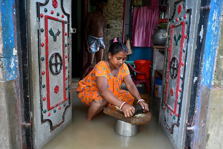 A flood-affected villager prepares spices for cooking inside her flooded house in Howrah district of India’s West Bengal state on October 2, 2021.