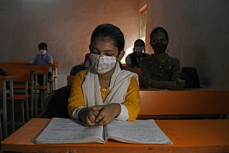 A student wearing a face mask is seen seated inside the classroom of Chhatrapati Shivaji Vidyalaya school as schools reopen in Mumbai from October 4, 2021, after remaining shut for a prolonged period amid the Covid-19 outbreak.