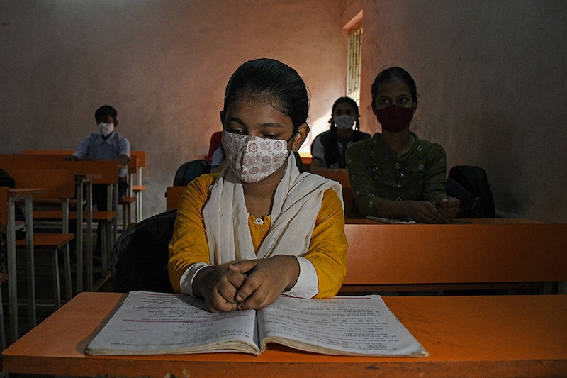 A student wearing a face mask is seen seated inside the classroom of Chhatrapati Shivaji Vidyalaya school as schools reopen in Mumbai from October 4, 2021, after remaining shut for a prolonged period amid the Covid-19 outbreak.
