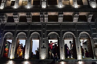Framed by ornate woodwork, residents avidly watch a Dussehra performance in the old quarters of Daraganj, Allahabad, October 9, 2021