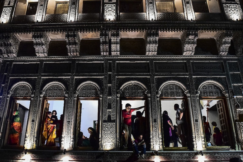 Framed by ornate woodwork, residents avidly watch a Dussehra performance in the old quarters of Daraganj, Allahabad, October 9, 2021