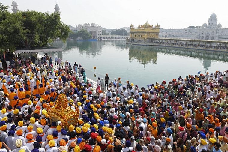Sikh devotees carry the Guru Granth Sahib (Sikh holy book) in a palanquin during a religious procession on the eve of the birth anniversary of the fourth Sikh Guru Ram Das at the Golden Temple in Amritsar on October 21, 2021.