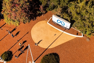An aerial view shows a person passing a newly unveiled logo for "Meta", the new name for Facebook"s parent company, outside Facebook headquarters in Menlo Park on October 28, 2021. - Facebook changed its parent company name to "Meta" on October 28 as the tech giant tries to move past being a scandal-plagued social network to its virtual reality vision for the future.