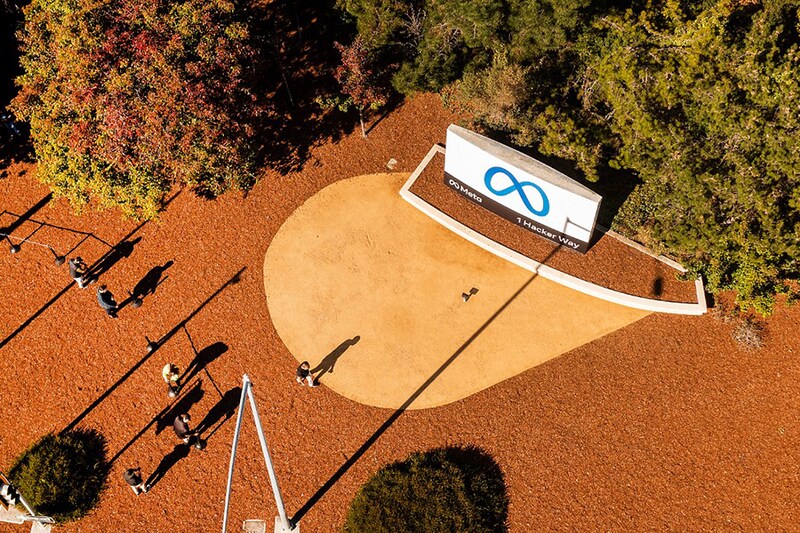 An aerial view shows a person passing a newly unveiled logo for "Meta", the new name for Facebook"s parent company, outside Facebook headquarters in Menlo Park on October 28, 2021. - Facebook changed its parent company name to "Meta" on October 28 as the tech giant tries to move past being a scandal-plagued social network to its virtual reality vision for the future.