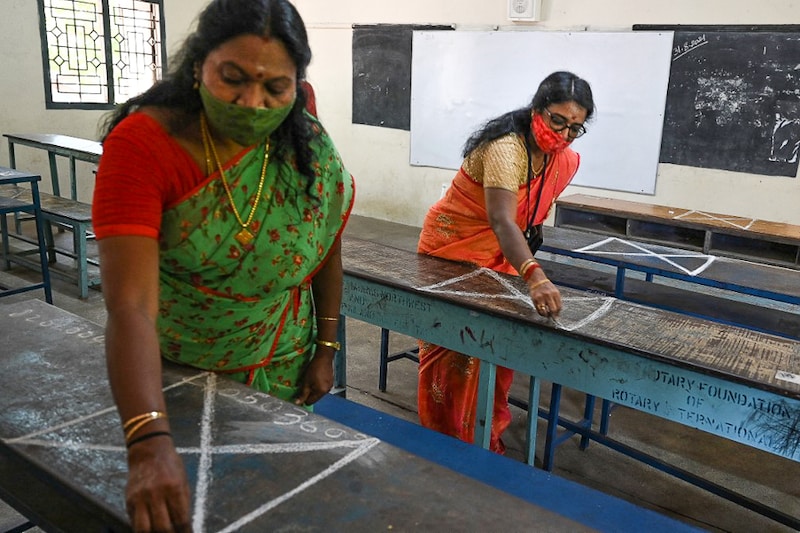 Teachers make social distancing markers on classroom benches at a school as they prepare for reopening after the Covid-19 lockdown relaxation in Chennai on August 31, 2021. On hearing a public interest litigation, the Tamil Nadu government informed the Madras High Court that school students would not be compelled to attend physical classes and can opt for online classes as an alternative.