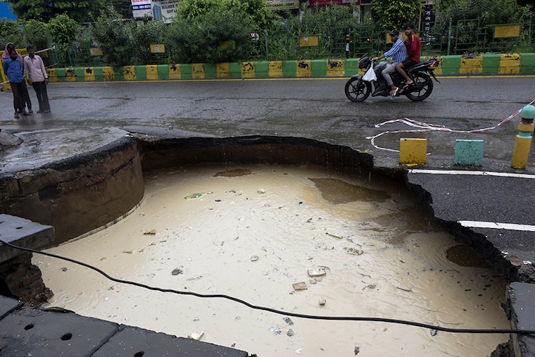 A portion of road caved in after heavy rains, at Indirapuram, Shipra Srishti, on September 11, 2021 in Ghaziabad, India. Delhi and its adjoining areas on Saturday woke up to a cloudy morning which soon gave way to heavy rain, in line with an orange alert issued by the India Meteorological Department (IMD).