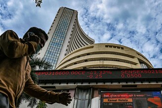 A pedestrian speaks on a phone as he walks past the Bombay Stock Exchange (BSE) in Mumbai on September 24, 2021. The Sensex touched a historic high of 60,000 today for the first time.