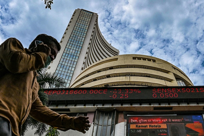 A pedestrian speaks on a phone as he walks past the Bombay Stock Exchange (BSE) in Mumbai on September 24, 2021. The Sensex touched a historic high of 60,000 today for the first time.