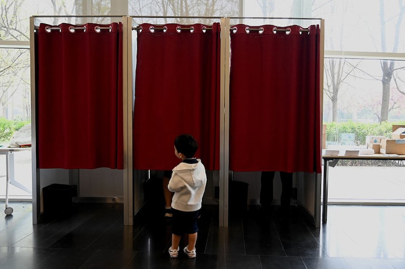 A child waits outside the booths as voters cast their ballots for the presidential election at the French Embassy in Beijing on April 10, 2022. France goes to the polls on April 10 in the first round of presidential elections projected to produce a run-off rematch between incumbent Emmanuel Macron and far-right leader Marine Le Pen that will be far tighter than their duel five years ago.