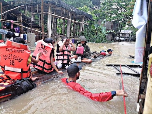 A coast guard personnel evacuating local residents from their flooded homes on a makeshift raft in the town of Panitan, Capiz province as heavy rains brought on by Tropical Storm Megi inundated the area. (Credit: AFP)