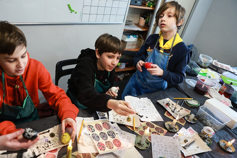 Ukrainian children—among many who fled from the eastern town of Kharkiv—prepare Easter eggs using melting wax on April 17, 2022, in Lviv, Ukraine. The Easter egg decorating project was put on by the Plast National Scout Organisation of Ukraine for children in Lviv, which has served as a stopover and shelter for the millions of Ukrainians fleeing the Russian invasion.
