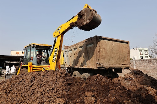 In this photograph taken on March 4, 2022, an excavator loads cow dung for biogas production into a truck at the dairy farm of farmer Suresh Sisodia in Mayakhedi village on the outskirts of Indore. India is tapping a new energy source that promises to help clean up smog-choked cities and is already providing a vital revenue stream for poor Indian farmers: truckloads of bovine manure. (Credit: Gagan NAYAR / AFP) In this photograph taken on March 4, 2022, an excavator loads cow dung for biogas production into a truck at the dairy farm of farmer Suresh Sisodia in Mayakhedi village on the outskirts of Indore. India is tapping a new energy source that promises to help clean up smog-choked cities and is already providing a vital revenue stream for poor Indian farmers: truckloads of bovine manure. (Credit: Gagan NAYAR / AFP)