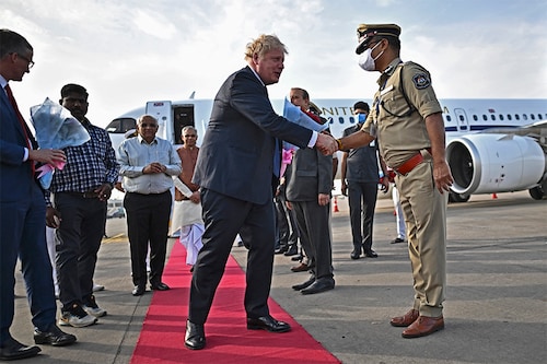 Britain"s Prime Minister Boris Johnson (C) is greeted by a police official upon his arrival at the airport in Ahmedabad on April 21, 2022. (Credit: BEN STANSALL / POOL / AFP)