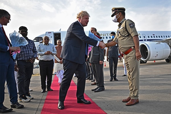 Britain"s Prime Minister Boris Johnson (C) is greeted by a police official upon his arrival at the airport in Ahmedabad on April 21, 2022. (Credit: BEN STANSALL / POOL / AFP)