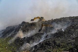 Workers operate excavators amidst burning garbage after a fire broke out at the Bhalaswa landfill in New Delhi on April 28, 2022. (Credit: Prakash SINGH / AFP)â€‹