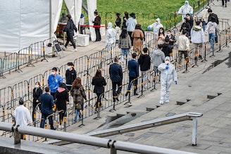 Security guards wear protective clothing as office workers queue for Covid-19 nucleic acid tests at a makeshift testing site on April 28, 2022, in Beijing, China. China is trying to contain a spike in coronavirus cases in the capital after dozens tested positive in recent days, prompting local authorities to initiate mass testing in most districts and to lock down some neighbourhoods where cases are found in an effort to maintain the country"s zero Covid strategy.